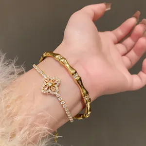 Close-up of gold-toned flower bracelet and bamboo-style bangle with zircon accents.