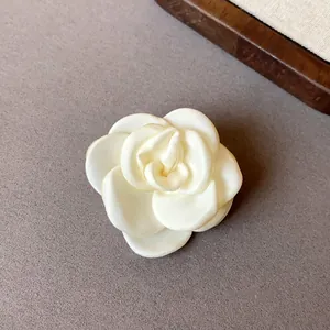 Close-up of a handmade ivory fabric rose hair accessory showing elegant petal textures.
