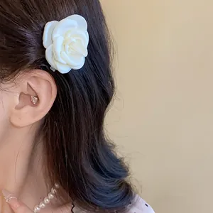 Detailed view of an elegant white camellia flower hair clip worn on long dark hair