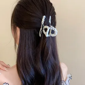 Back view of a woman wearing a white polka dot hair claw clip with a black bow
