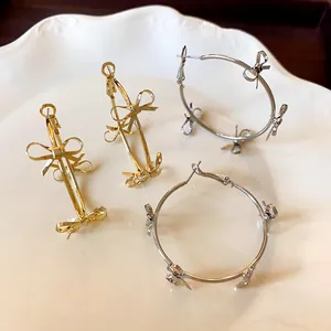 Dettaglio di orecchini a cerchio oro e argento con fiocchi su un piatto bianco