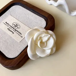 Close-up detail of a cream white fabric rose hair clip with silky petal texture