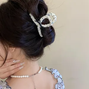 Detail of French style polka dot fabric wrapped hair claw clip with black bow accent