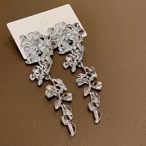 Elegant silver metal flower and leaf tassel drop earrings on a white display card