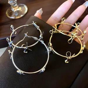 Dettaglio ravvicinato di eleganti orecchini a cerchio con fiocco in argento e oro