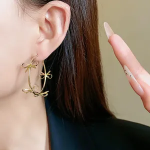 Dettaglio di grandi orecchini a cerchio dorati con eleganti fiocchi per uno stile unico