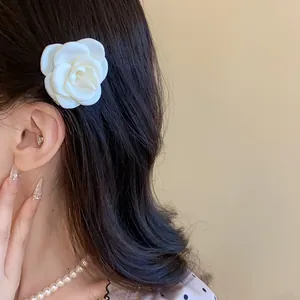 Detail showing an elegant white camellia flower hair clip worn on long black hair