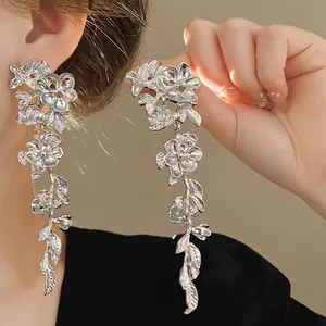 Close-up detail of silver floral tassel earrings with delicate leaf design on model.