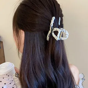 Close-up detail of a stylish white polka dot bow hair claw clip used in a messy bun