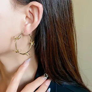 Primo piano di una modella con grandi orecchini a cerchio dorati con delicati fiocchi.