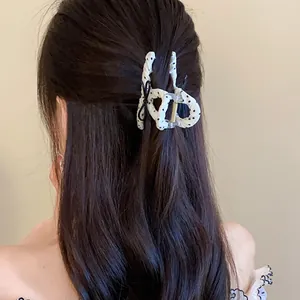 Close-up detail of an elegant white polka dot hair claw clip with a black bow on long brown hair