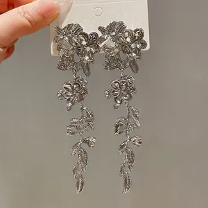 Detailed macro shot of silver metallic floral tassel earrings with delicate petal patterns.