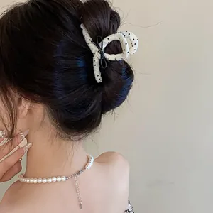 Close-up of a French style polka dot hair claw clip with black bow detail on hair