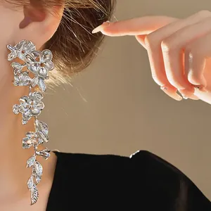 Close-up of elegant silver-toned floral tassel earrings worn on ear with soft lighting