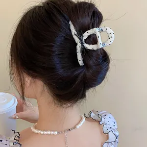 Macro detail of a French style polka dot hair claw clip with a black bow on an updo