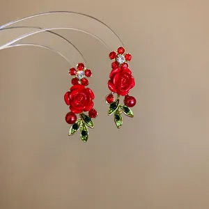 Detailed macro view of elegant red rose earrings with rhinestones and green leaves
