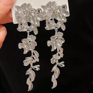 Detail of silver floral tassel earrings with intricate leaf drops on black backdrop