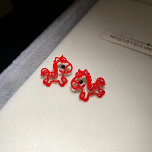 Close-up of red hollow horse stud earrings with sparkling black stone accents