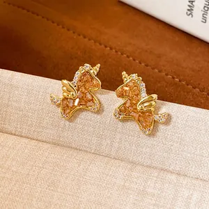 Macro view of gold-plated unicorn stud earrings with sparkling crystal pavé accents