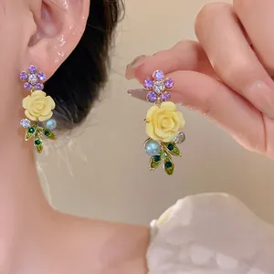 Elegant floral earrings with yellow roses, purple petals, and pearl leaf details