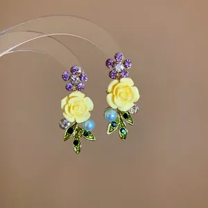 Exquisite floral earrings featuring yellow rose, purple rhinestones, blue pearl and green leaves