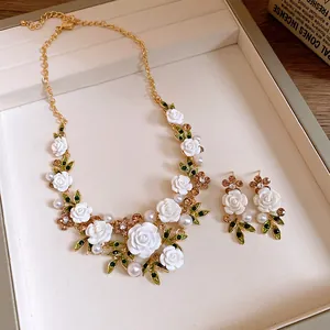 Close-up detail of white flower and leaf necklace set with pearls and crystals