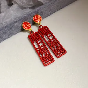 Close-up of red festive drop earrings with Chinese characters Fu and Get Rich