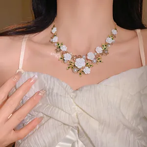 Detailed view of elegant floral necklace featuring white roses, pearls and green leaves decoration