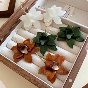 Close-up of vintage resin flower earrings in white, green, and amber inside a jewelry box