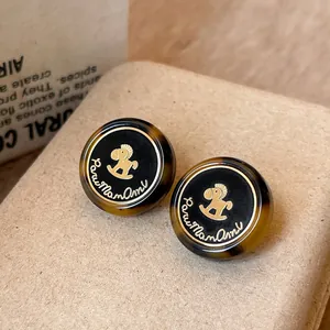 Detail view of vintage tortoiseshell stud earrings with a gold rocking horse motif.
