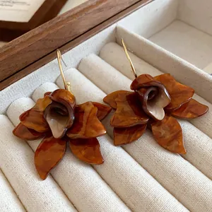 Close-up macro view of vintage amber resin flower earrings resting in a beige jewelry box