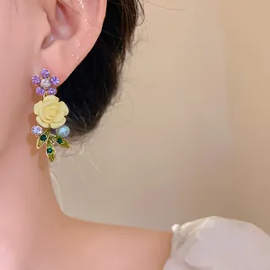 Detailed close-up of a floral earring with purple rhinestones and a yellow rose