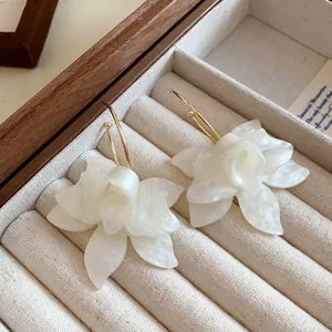 Detailed macro view of elegant white resin flower earrings inside a velvet jewelry box