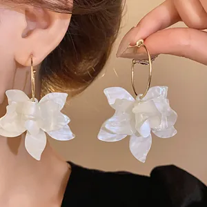 Close-up of white resin flower hoop earrings with an elegant pearl-like finish.