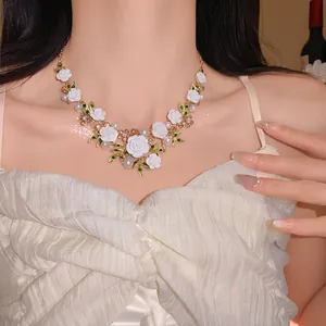 Detailed view of sweet floral necklace with white roses, green leaves and pearls on model.