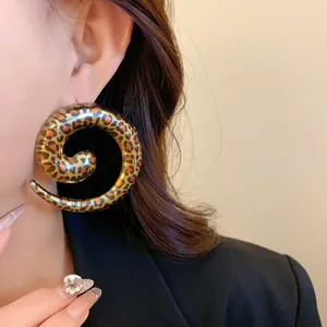 Close-up detail of a bold spiral leopard print earring worn by an elegant Asian model