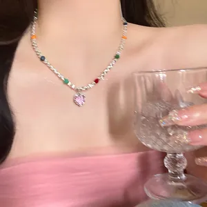 Detailaufnahme einer silbernen Perlenkette mit rosa Herzanhänger an einem Model