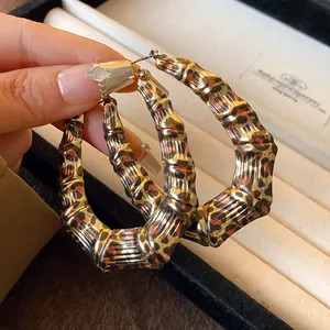 Close-up detail of large bamboo-textured hoop earrings with leopard print pattern