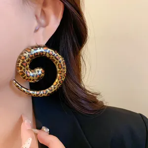 Detailed macro shot of an oversized geometric spiral earring with bold leopard print pattern