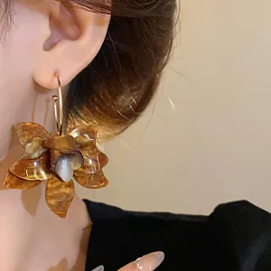 Detailed close-up of a vintage resin flower earring with brown tortoise pattern