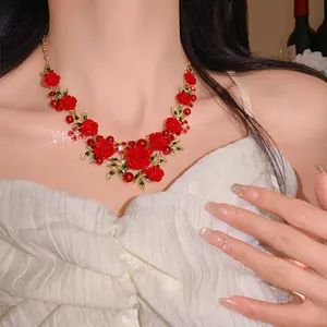 Detailed view of an elegant red rose and green leaf necklace with pearls on a model