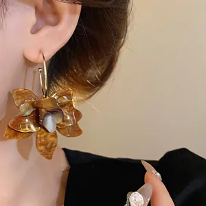 Detailed close-up view of a vintage amber resin flower earring worn on a model's ear