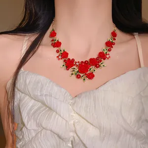 Detail view of a pastoral style necklace featuring red roses, green leaves, and pearls
