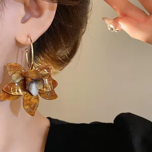 Close-up view of vintage resin flower earrings with amber tortoise-shell pattern worn by model