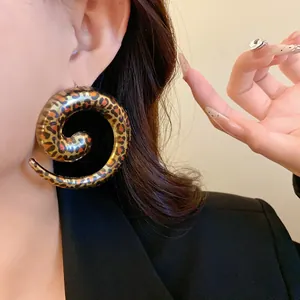 Close-up detail of oversized leopard print spiral hoop earrings worn by a model