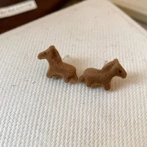 Macro view showing the brown flocked texture of these cute horse-shaped stud earrings