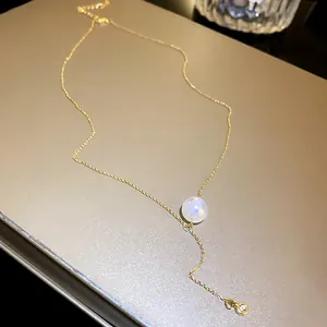 Detailed macro view of an elegant gold necklace featuring a shimmering mermaid pearl pendant.