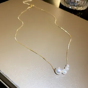 Close-up view of an elegant French style gold necklace with four graduated pearls
