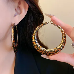 Detailed close-up view of oversized leopard print hoop earrings shown on a model