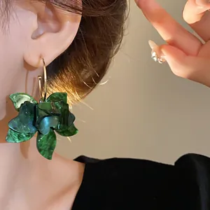 Detail view of vintage green resin flower hoop earrings worn on a model's ear